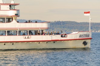 Ship with Austrian flag on calm water with landscape background, boat trip, Lake Constance, Germany