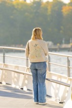 Rear view of woman standing on a boat deck looking at nature, Schiff Fahrt, Lake Constance, Germany
