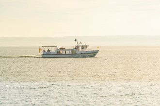 A small boat sails quietly across a lake with gentle waves to the horizon, boat trip, Lake