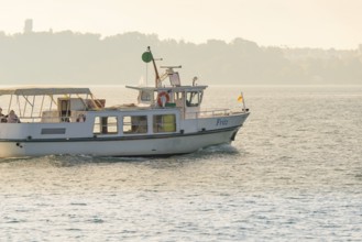 Small boat on a quiet lake near the coast with parasol and flag, boat trip, Lake Constance, Germany