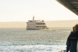 A passenger ferry sails on a wide lake towards the horizon, Schiff Fahrt, Lake Constance, Germany
