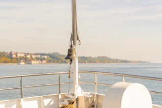 View of the water from a ship with a railing and a bell in the foreground, Schiff Fahrt, Lake
