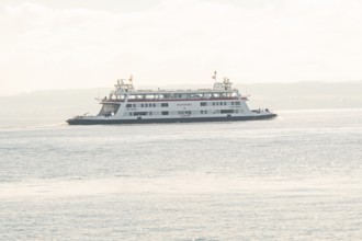 Ferry sails on a calm lake under a pastel colored sky, boat trip, Lake Constance, Germany