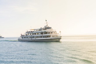 A large ship sails across a sunny lake with a warm glow of light, boat trip, Lake Constance,