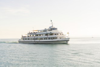 A white passenger liner sails across a still lake under a clear sky, boat trip, Lake Constance,