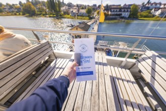Brochure is being held on a ship heading towards the pier, Schiff Fahrt, Lake Constance, Germany