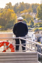 Captain standing at the helm of a boat with an autumn view, boat trip, Lake Constance, Germany