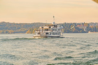 A passenger ship glides on a lake along an autumnal coastal landscape, boat trip, Lake Constance,