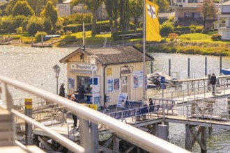 Jetty with buildings in the background under autumn sun, boat trip, Lake Constance, Germany