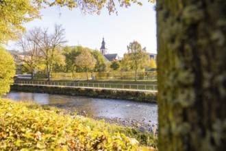 River landscape with church surrounded by autumn trees, Nagold, Black Forest, Germany
