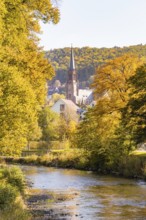 River landscape with a view of a church and autumn trees in a small village, Nagold, Black Forest,