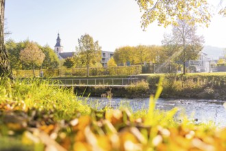 Idyllic river course in autumn with view of a church and colorful trees, Nagold, Black Forest,