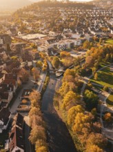 A river flows through an autumnal urban landscape, surrounded by parks and colorful trees, Nagold,