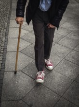 DEU Germany Germany Berlin Old man with a crutch walking through the German capital wearing