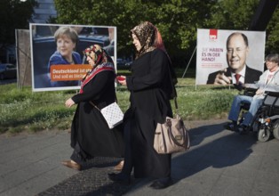 DEU Germany Germany Berlin Two Muslim woman and a man in a wheelchair pass the election posters of