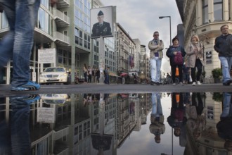 DEU Germany Germany Berlin Tourists at Checkpoint Charlie reflecting in a puddle after rain