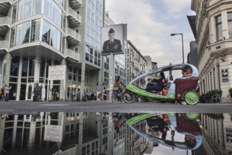 DEU Germany Germany Berlin Tourists at Checkpoint Charlie reflecting in a puddle after rain
