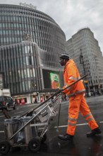 DEU Germany Berlin An employee of Stadtreinigung BSR pushes his handcart across a block of