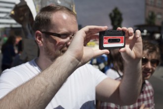 DEU Germany Germany Berlin tourist takes pictures with dummy cassette tape at Checkpoint Charlie