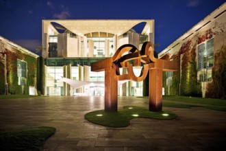 Illuminated Federal Chancellery in the evening with the sculpture entitled Berlin by Eduardo