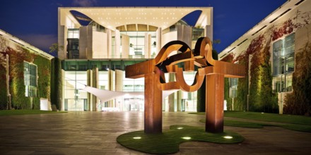 Illuminated Federal Chancellery in the evening with the sculpture entitled Berlin by Eduardo