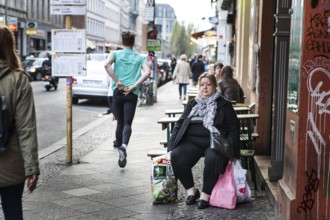 DEU Germany Germany Berlin An overweight woman is waiting for the bus with shopping bags.