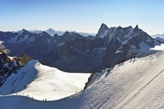Mountaineers climb over a snow-covered mountain ridge, behind Grandes Jorasses, viewing platform,