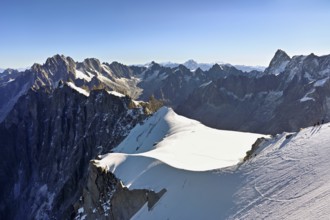 Mountaineers climb over a snow-covered ridge, behind Aiguille Verte, Les Droites, Les Courtes,