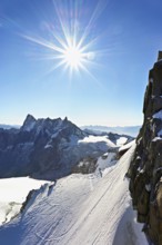 Mountaineers climb over a snow-covered ridge, behind Grandes Jorasses, Aiguille du Midi mountain