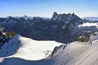 Mountaineers climb over a snow-covered mountain ridge, behind Grandes Jorasses, viewing platform,