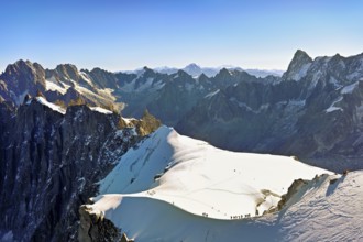 Mountaineers climb over a snow-covered ridge, behind Aiguille Verte, Les Droites, Les Courtes,