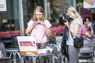 DEU Germany Germany Berlin Girls photograph a box of donuts they just bought in front of a Dunkin