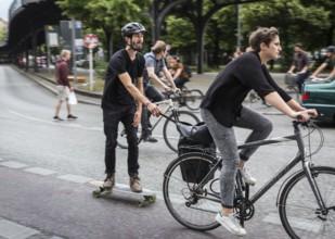 DEU Germany Germany Berlin female cyclist pulls skateboarders on Skalitzer Straße in Kreuzberg