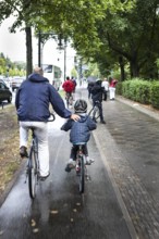 DEU Germany Germany Berlin Cyclists have their arms on a child's back as they cycle towards the