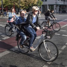 DEU Germany Germany Berlin cyclist transports a man on the luggage rack while another woman watches