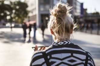 DEU Germany Germany Berlin Woman holds her smartphone while she is telephoning across the square at