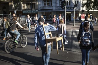 DEU Germany Germany Berlin Man with a chair over his shoulder crosses a pedestrian traffic light on