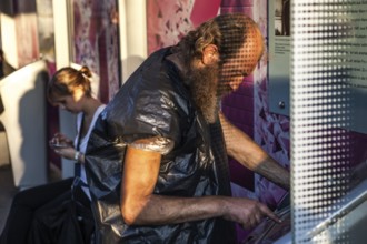DEU Germany Germany Berlin Homeless person with plastic bag and feet connected to plastic at a bus