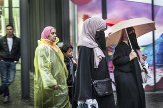DEU Germany Germany Berlin Women wearing headscarves and face veils walking through the rain on