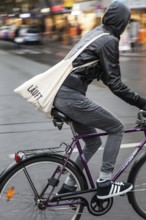 DEU Germany Germany Berlin female cyclist with cloth bag crosses a street in the capital