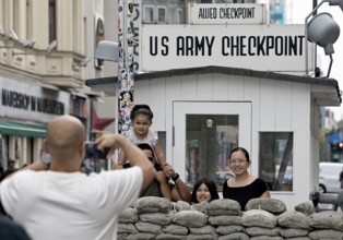 Tourists take a souvenir photo at Checkpoint Charlie, Berlin, Germany