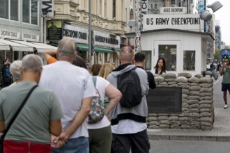 Tourists at Checkpoint Charlie queue for a souvenir photo, Berlin, Germany
