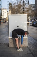 DEU Germany Germany Berlin A jogger does gymnastics in front of an Apple shop display case on