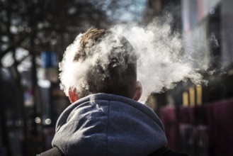 DEU Germany Germany Berlin Smoke from an e-cigarette envelops a man's head on Kudamm