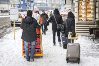 DEU Germany Germany Berlin Travelers with wheeled suitcases pass by beverage purveyors on a