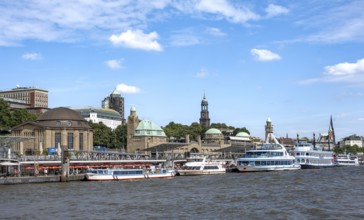 Elbe and boats at the St. Pauli piers, historic building with a level tower, in the back church