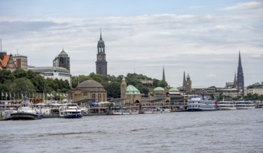 Elbe and boats at the St. Pauli piers, historic building with a level tower, in the back church