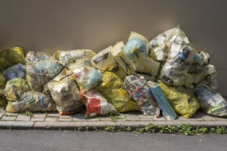 Yellow bags for plastic waste are lying on the side of the road, waste separation, waste disposal,