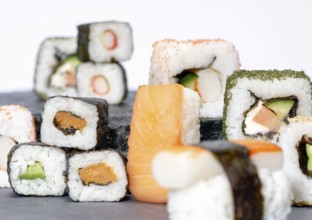 Various sushi dishes on dark grey stone surface