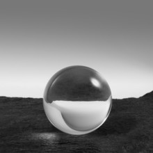 A clear crystal ball on rough dark grey stone surface in front of red back